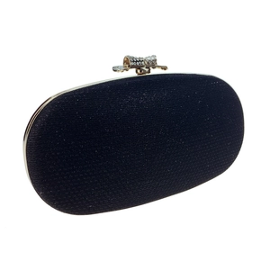 Detail of evening clutch bag featuring a gold bow clasp with micro-set rhinestones