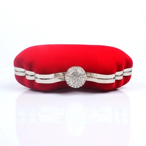 Macro detail of red velvet clutch bag featuring a sparkling round rhinestone clasp and silver frame