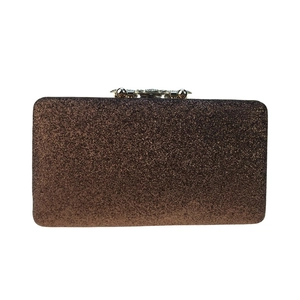 Macro shot of brown sequined surface with gold floral clasp on evening clutch bag