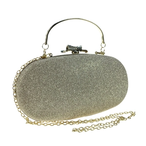 Detail of glitter evening clutch featuring rhinestone bow clasp and gold metal handle