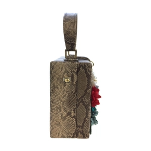 Détail de la texture serpent et des embellissements floraux 3D sur un sac à main