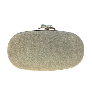 Macro shot of sparkling champagne evening clutch with rhinestone bow clasp detail