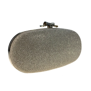 Close-up of elegant champagne gold evening clutch with a sparkling rhinestone bow clasp