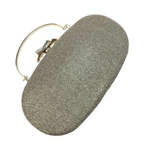 Macro view of champagne gold evening bag with glitter texture and rhinestone bow clasp