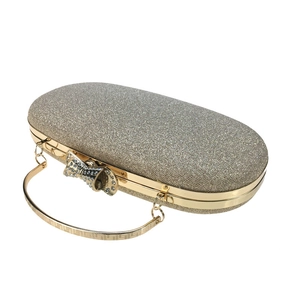 Detail of champagne gold evening clutch with glitter texture and rhinestone bow clasp