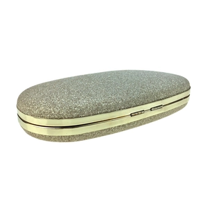 Detail of the golden glitter texture and metallic frame on the oval evening clutch bag