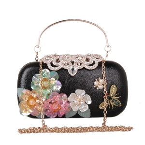 Close-up of 3D sequin flowers, pearl accents, and bee embroidery on black evening clutch