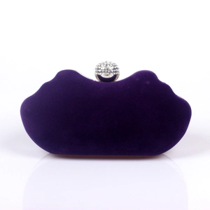 Macro detail of deep purple velvet clutch featuring a silver frame and crystal ball clasp