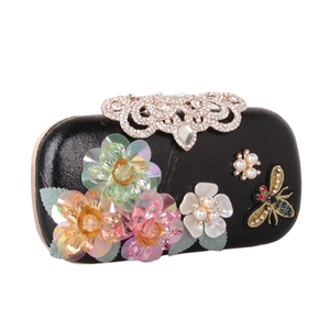 Detail of black clutch with 3D sequin flowers, pearls, bee embroidery and rhinestone clasp
