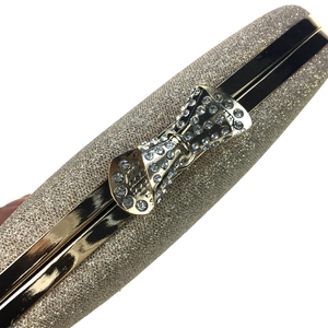 Detail of glitter evening clutch featuring a gold metal frame and rhinestone bow clasp