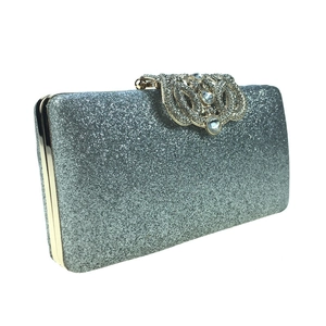 Macro view of silver sequined evening clutch bag with crystal floral metal clasp