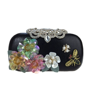 Close-up of black evening bag with sequin flowers, pearl accents and crystal clasp