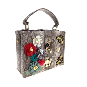 Détail du sac serpent avec accents floraux 3D et broderie d'abeille dorée
