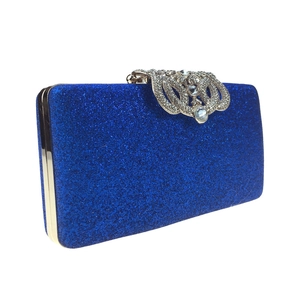 Close-up of royal blue glitter clutch with luxury crystal-encrusted crown metal clasp