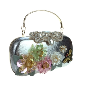 Detail of silver sequined evening clutch with 3D floral accents and a rhinestone clasp