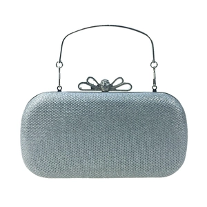 Détail de la pochette argentée pailletée avec fermoir nœud en strass et poignée