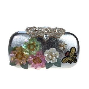 Detail of silver evening bag with 3D floral sequins, rhinestone clasp and bee embroidery