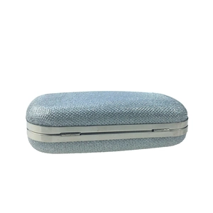 Vue détaillée de la texture pailletée argentée et du cadre métallique de la pochette de soirée