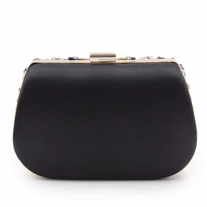Detail of black satin evening clutch with gold metal frame and blue rhinestone accents