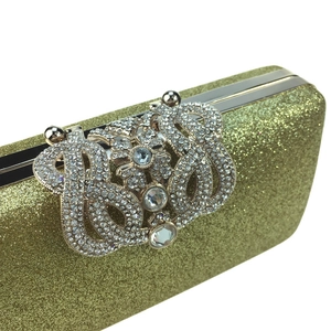 Detail of glitter fabric and sparkling rhinestone crown clasp on gold evening clutch bag