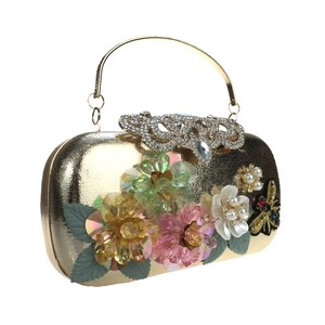 Detail of luxury gold evening clutch featuring 3D crystal flowers and pearl embellishments