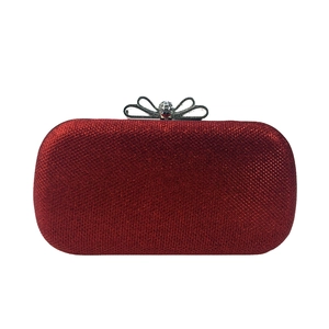Détail d'une pochette de soirée à paillettes rouges avec fermoir nœud en diamant brillant