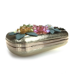 Detailed view of 3D crystal flowers and pearl embellishments on a golden evening clutch