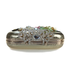 Detailed view of luxury gold evening clutch with crystal crown clasp and pearl floral accents