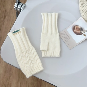 Detail view of white cable knit fingerless gloves with soft texture and brand label