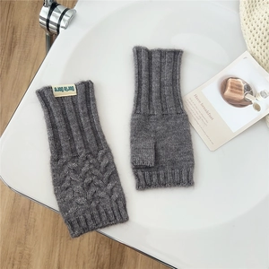 Detailed close-up of dark grey knitted fingerless gloves with cable stitch texture