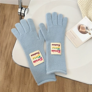 Close-up of light blue knitted gloves featuring a fashionable white brand label detail