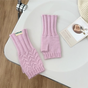 Close-up of pink cable knit fingerless gloves with ribbed cuffs and leaf pattern detail