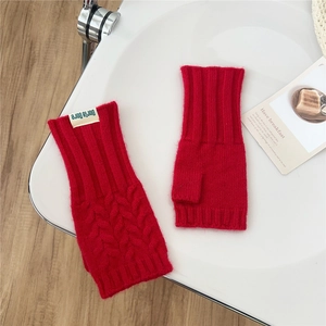 Detailed close-up of red cable-knit fingerless gloves with soft wool texture and ribbing