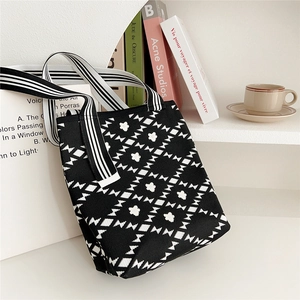 Detail of knit tote bag with black and white floral diamond pattern on shelf