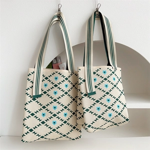 Close-up of knit tote bag featuring green geometric patterns and blue floral details