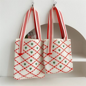Close-up of knit tote bag with red geometric patterns and floral details on white fabric