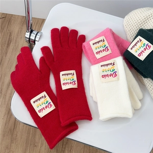 Colorful knitted winter gloves in wool texture with ribbed cuffs and fashion label