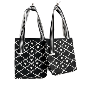 Set of two black and white knitted tote bags with floral patterns and striped straps