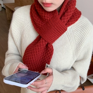 Detail of reddish-brown waffle knit scarf with ribbed edges on woman in cream sweater