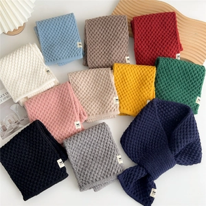 Close-up of waffle knit texture on warm scarves in 11 colors stacked on a table