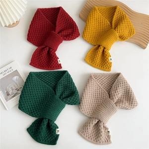 Minimalist knit cross scarves in mustard, red, and beige shown in a cozy flat lay arrangement