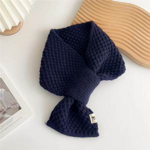 Close-up of navy blue waffle knit cross scarf showing soft texture and woven label