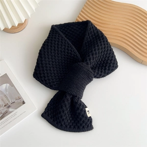 Detail of black honeycomb knit scarf with crossover closure and soft wool texture