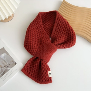 Detail of dark red knit scarf with waffle texture and unique cross-tuck closure design