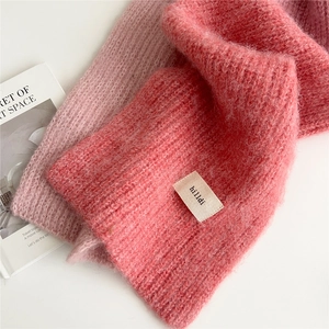 Detailed close-up of soft pink mohair knit scarf with a stylish minimalist brand label