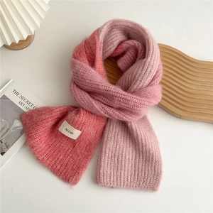Close-up of a soft pink gradient knit scarf with fluffy texture and branded tag detail