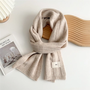 Detail of oatmeal knit scarf showing vertical stripe texture and minimalist emo label