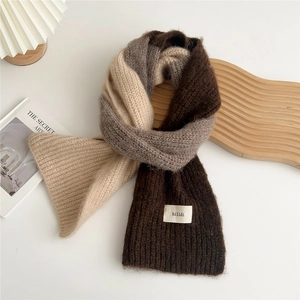 Close-up of thick knitted scarf with three-color patchwork and hilldi woven label