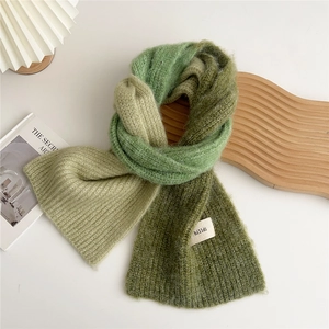 Close-up of green gradient knit scarf with soft mohair texture and brand label