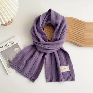 Detailed texture of purple ribbed knit scarf with a minimalist emo fabric label